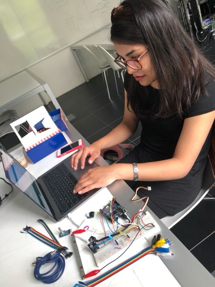 Diana coding at a laptop next to an Arduino breadboard prototype